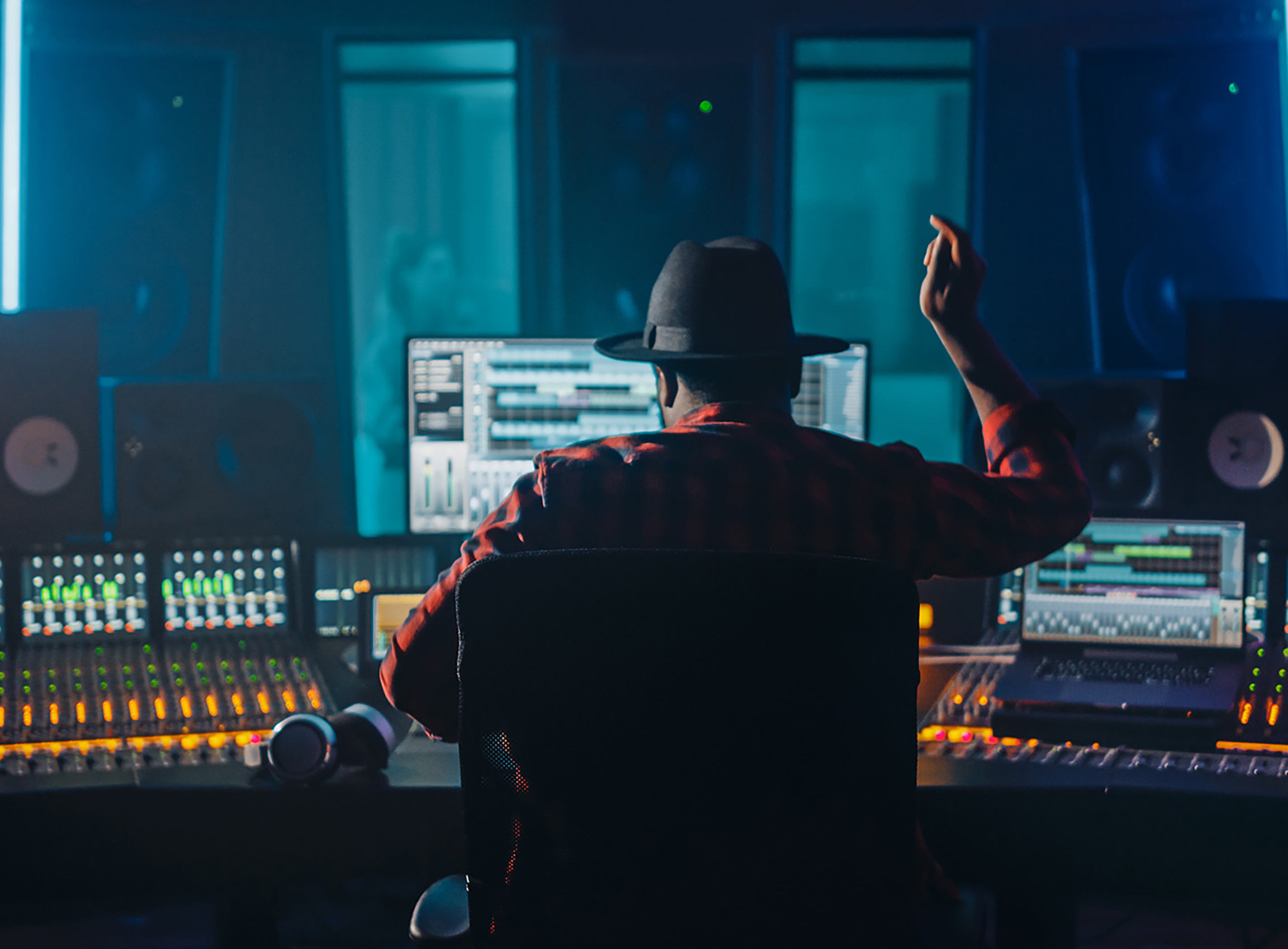 man with hat producing music in studio.